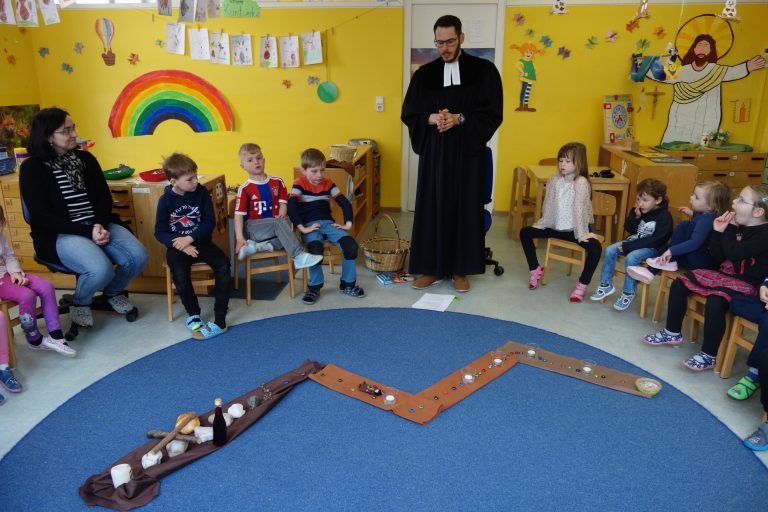 Der evangelische Pfarrer Herr Fischer stellt sich vor und bringt den Kindern eine religiöse Legegeschichte mit