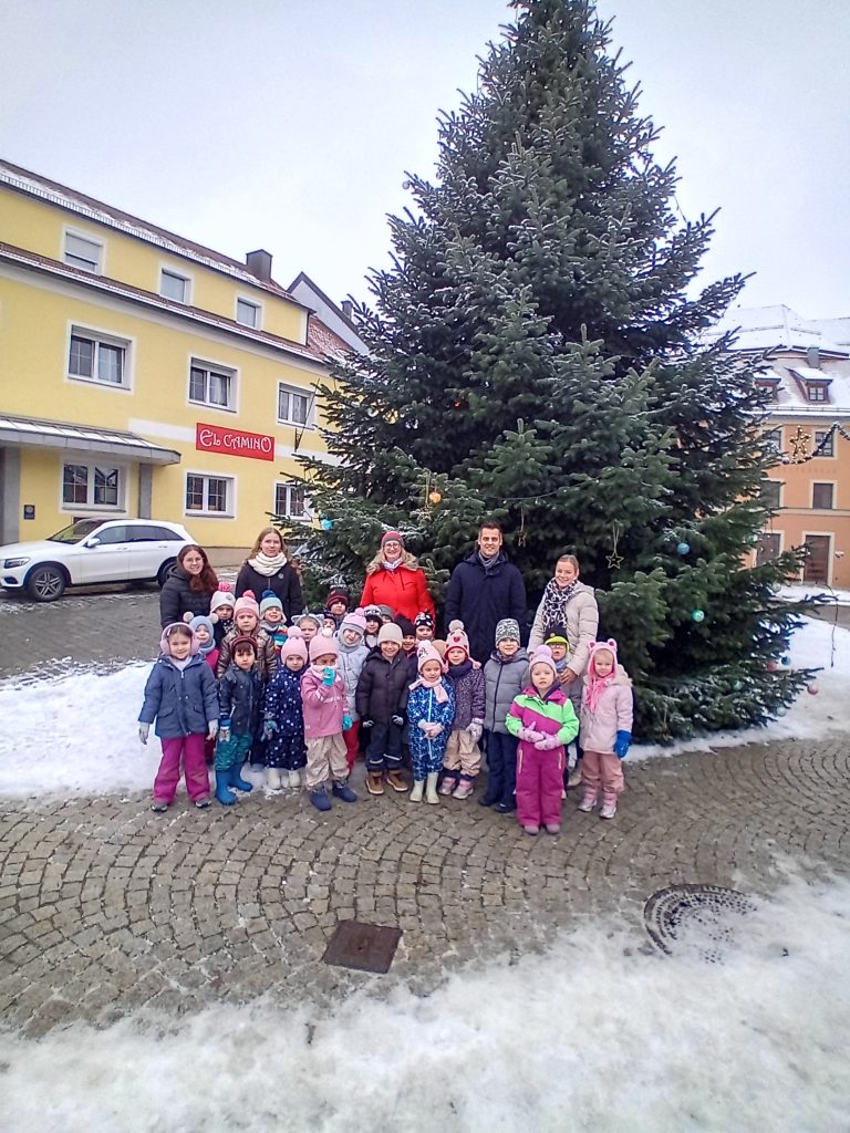 Wir hängen unsere selbst gebastelten Kugeln an den Baum am Marktplatz. Bürgermeister Hr. Teplitzky und einige Stadtmitarbeiter helfen uns dabei.