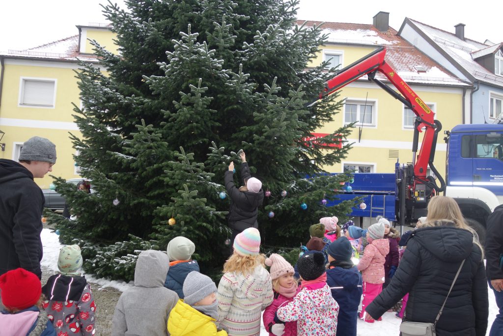 Wir hängen unsere selbst gebastelten Kugeln an den Baum am Marktplatz. Bürgermeister Hr. Teplitzky und einige Stadtmitarbeiter helfen uns dabei.