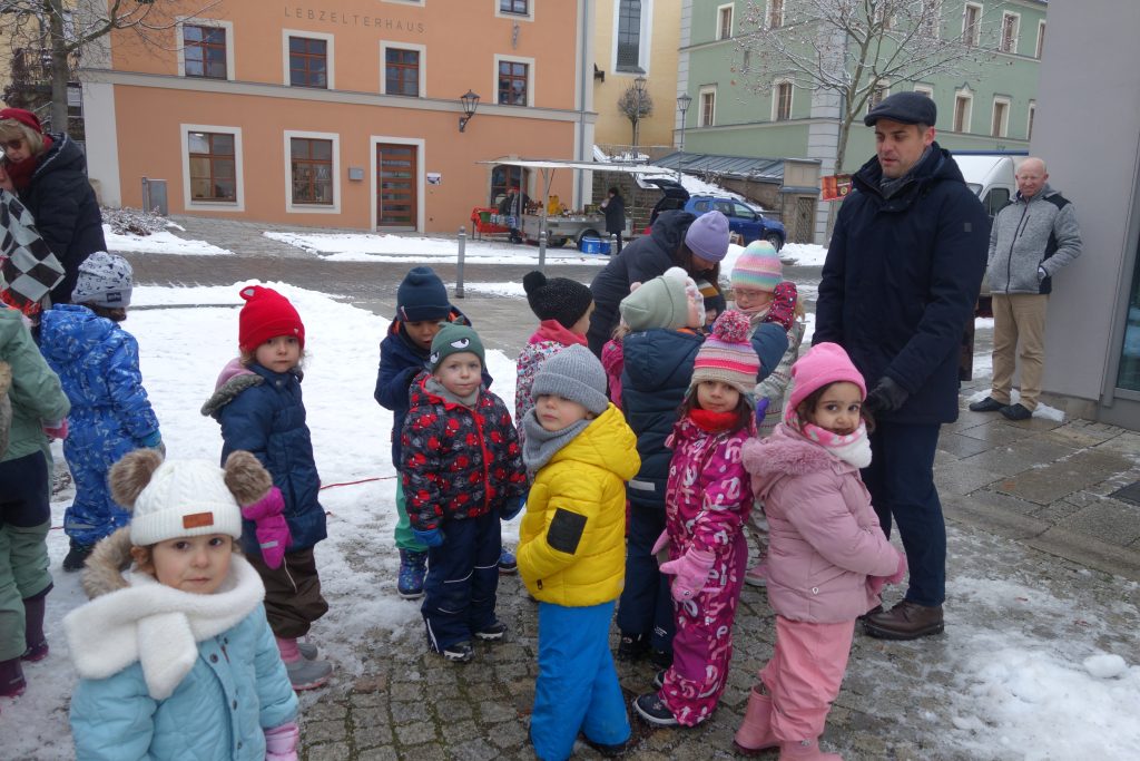 Wir hängen unsere selbst gebastelten Kugeln an den Baum am Marktplatz. Bürgermeister Hr. Teplitzky und einige Stadtmitarbeiter helfen uns dabei.