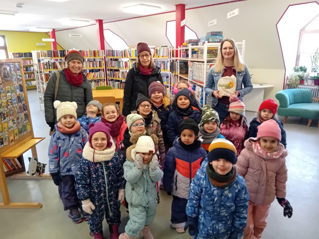 Wir besuchen die Bücherei. Frau Hagl überreicht der Katzengruppe eine Büchertasche.