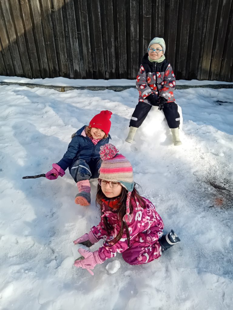 Die Kinder spielen im Schnee und bauen mit großer Begeisterung einen Schneemann. ⛄
