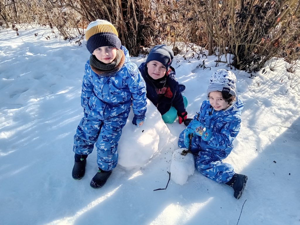 Die Kinder spielen im Schnee und bauen mit großer Begeisterung einen Schneemann. ⛄